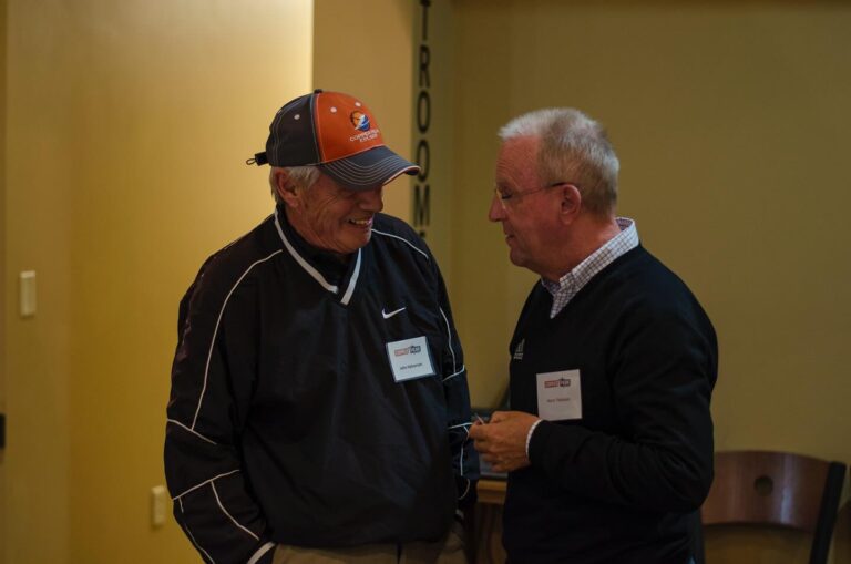 Two men standing in a meeting room discussing ski jumping